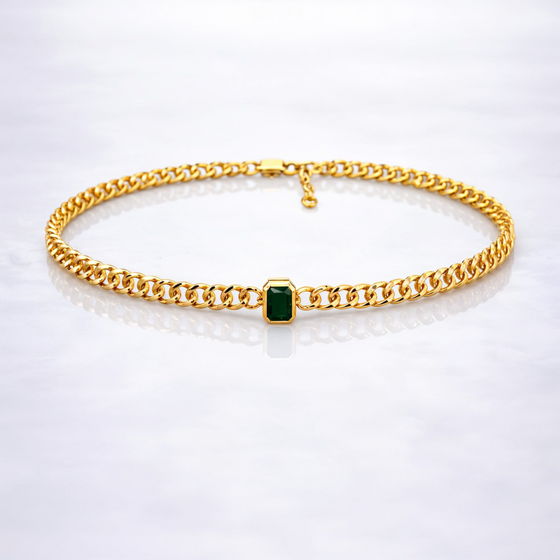 Gold  plated brass necklace with a green gemstone on a grey background