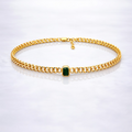 Gold  plated brass necklace with a green gemstone on a grey background