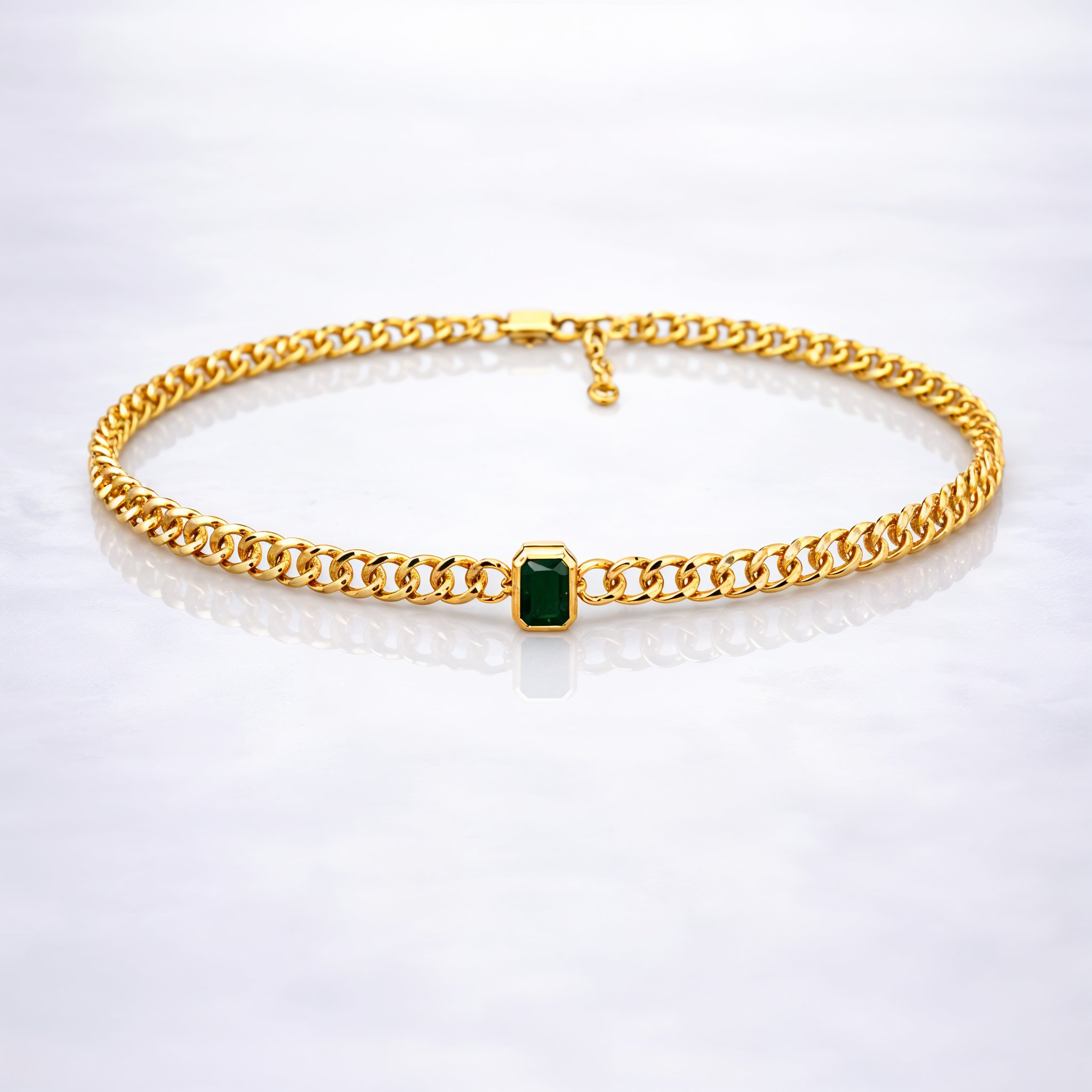 Gold  plated brass necklace with a green gemstone on a grey background