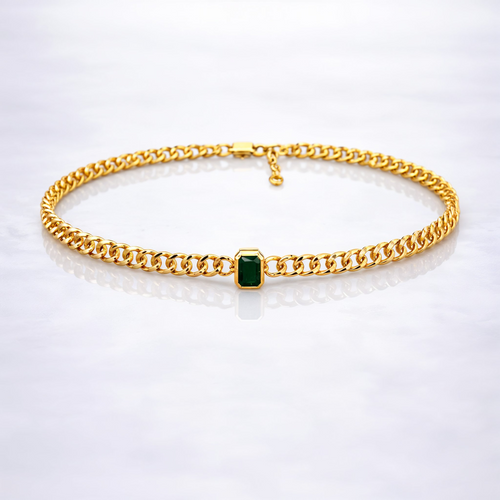 Gold  plated brass necklace with a green gemstone on a grey background
