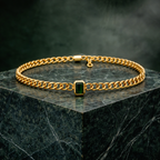 Gold plated brass necklace with a green gemstone on a dark green marble surface