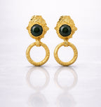 Pair of gold plated brass earrings with green gemstones on a grey background
