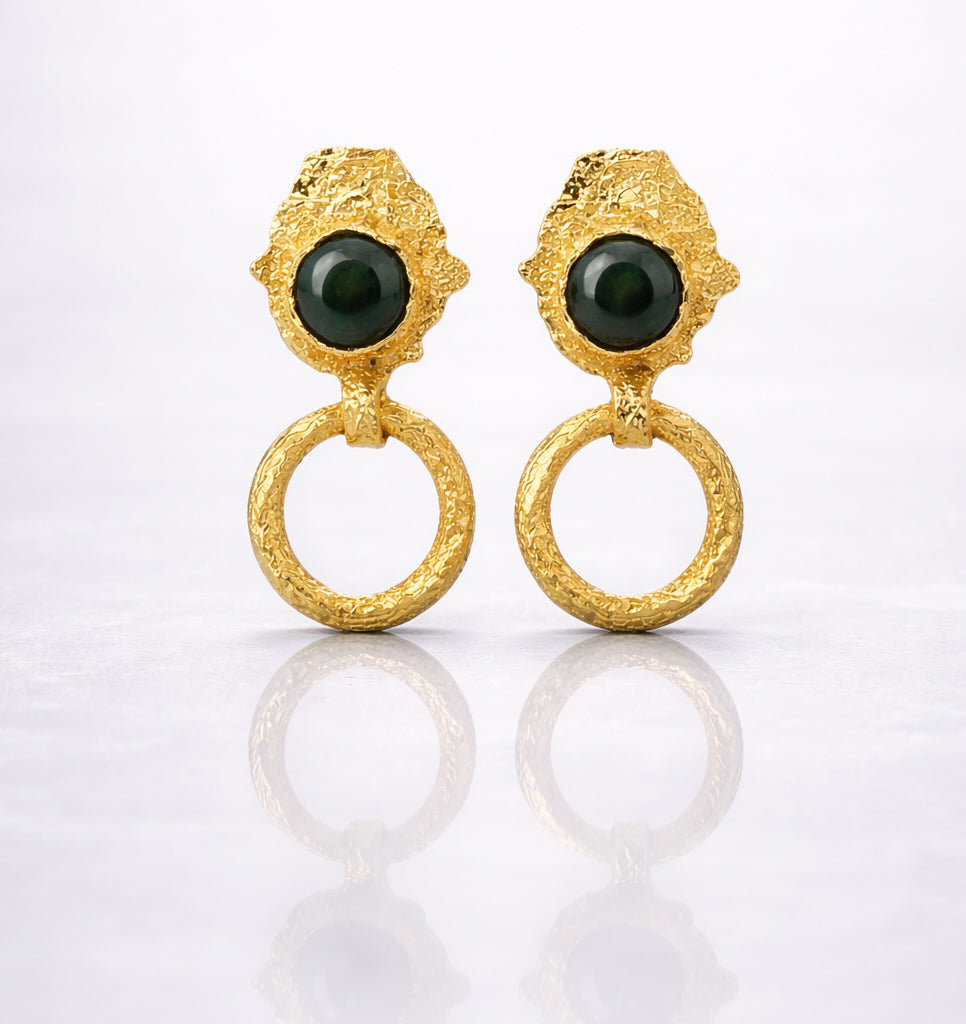 Pair of gold plated brass earrings with green gemstones on a grey background