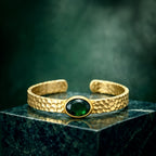 Gold plated brass bracelet with a green gemstone on a person's wrist, wearing a dark green stone.