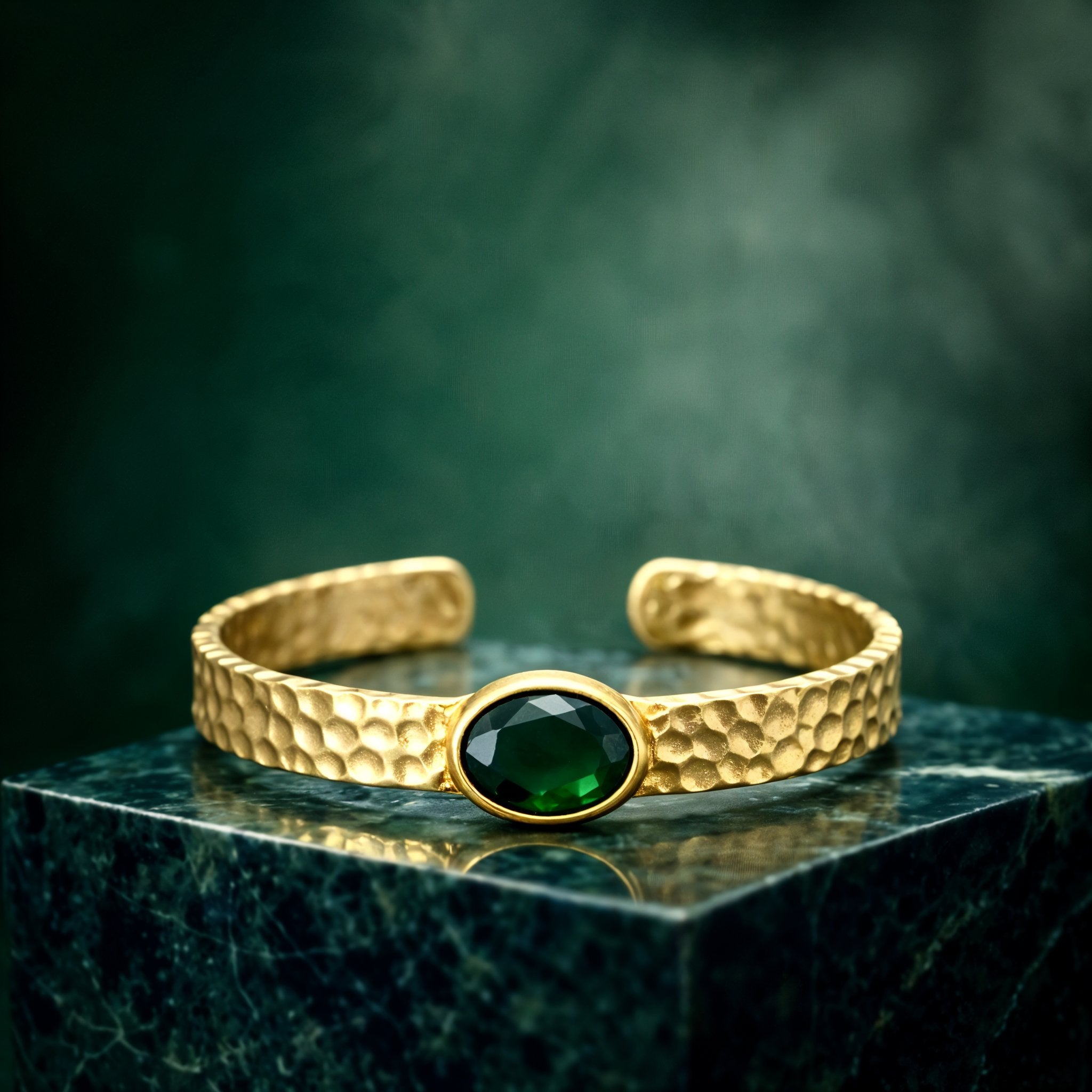 Gold plated brass bracelet with a green gemstone on a person's wrist, wearing a dark green stone.