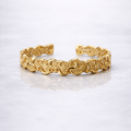 Gold plated brass bracelet with a pattern on a grey marble background