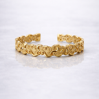 Gold plated brass bracelet with a pattern on a grey marble background
