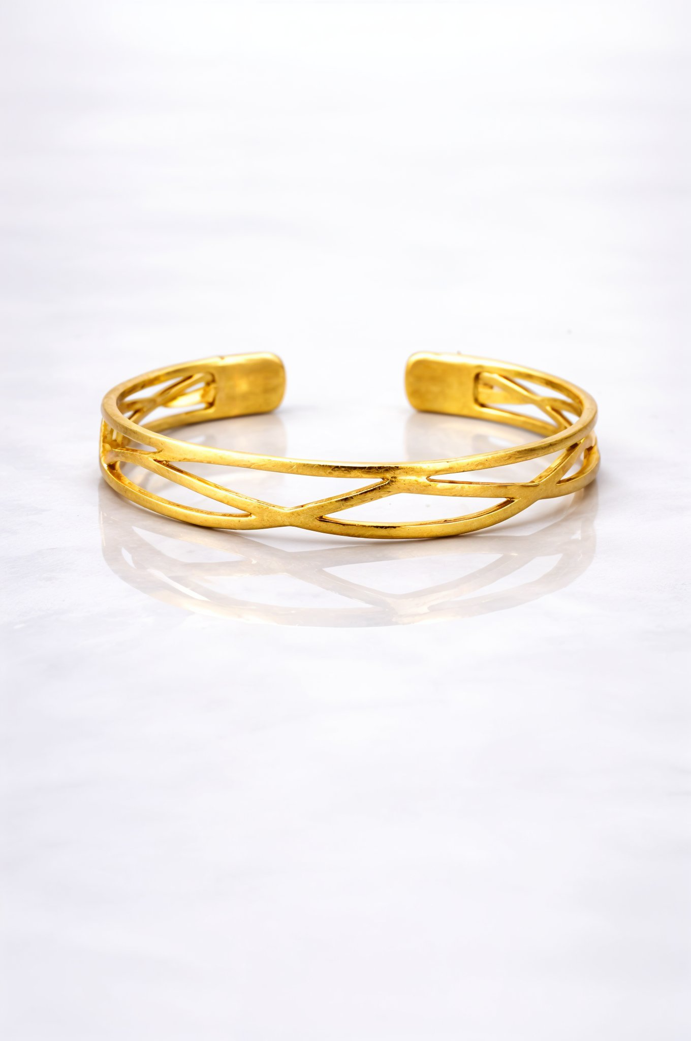 Gold plated brass bracelet on a grey marble surface 