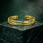 Gold plated brass bracelet on a dark marble surface with a dark background